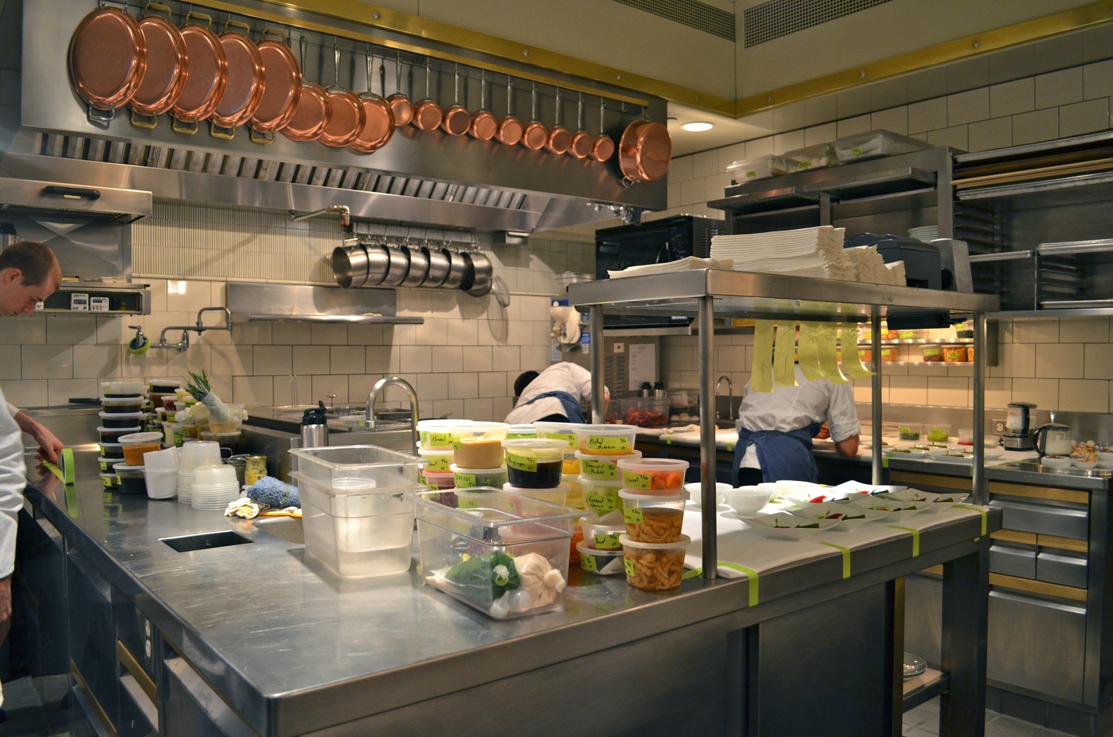 Chefs at work among stainless-steel prep counters and organized ingredients in a professional kitchen